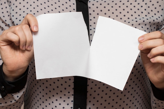 Manos femeninas rasgando una hoja de papel, primer plano.