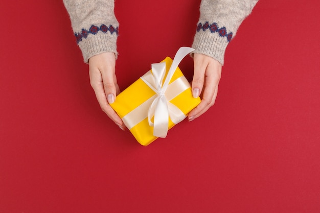 Manos femeninas con regalo de navidad en rojo