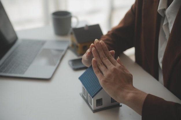 Manos femeninas salvando casita con techo