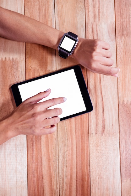 Manos femeninas con smartwatch usando tableta