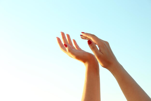 Manos femeninas sobre el fondo del cielo azul