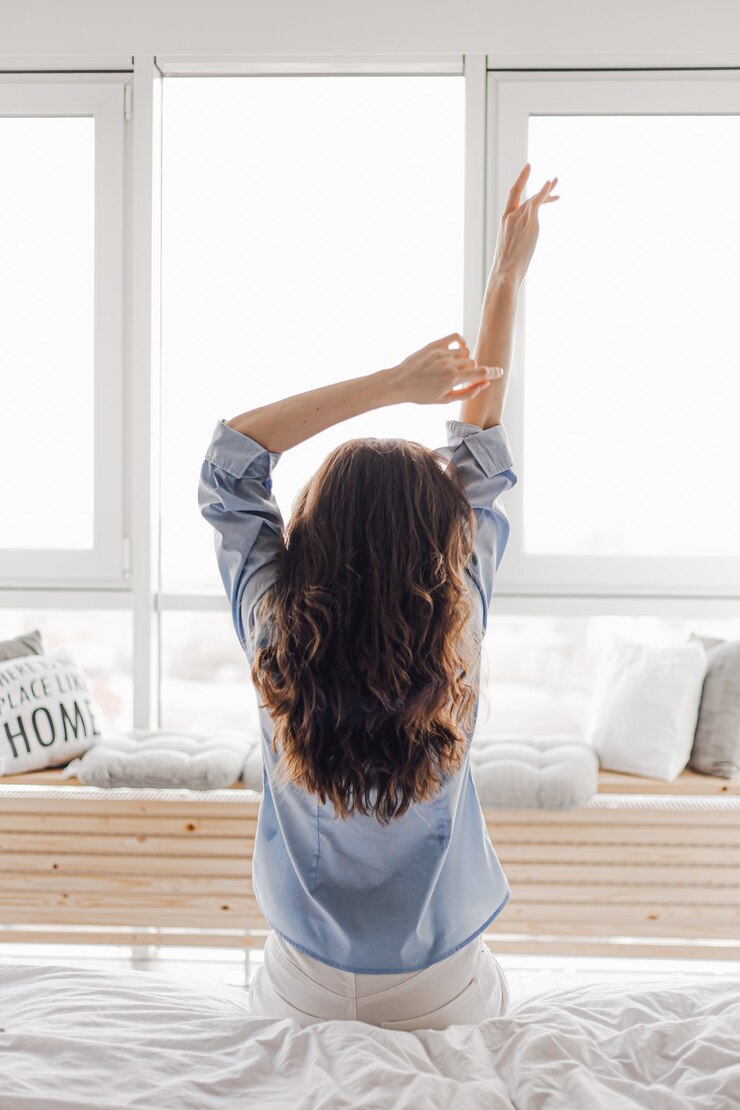 Manos femeninas sobre un fondo de una ventana. Mujer despertando estirando en la cama en su casa. Temprano en la mañana y despertar descansar día soleado. Concepto de estilo de vida