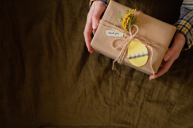 Manos femeninas sosteniendo cajas de regalo decoradas con flores amarillas con palabras de gratitud