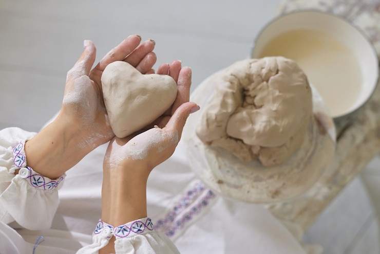 Foto manos femeninas sosteniendo una cerámica de corazón de arcilla