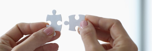 Manos femeninas sosteniendo dos piezas de un rompecabezas blanco closeup concepto de trabajo en equipo