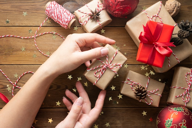 Foto manos femeninas sosteniendo, envolviendo la caja de regalo de navidad.