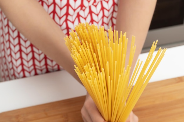 Manos femeninas sosteniendo espaguetis en la cocina