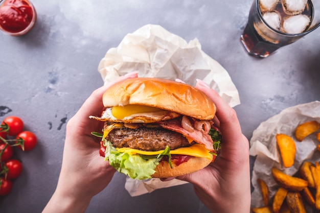 Manos femeninas sosteniendo jugosa hamburguesa de ternera