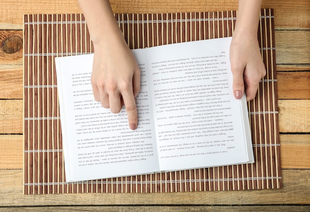 Manos femeninas sosteniendo el libro abierto en la estera