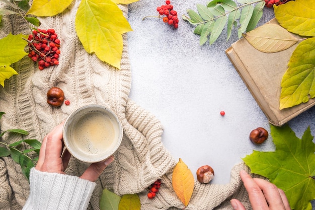 Manos femeninas sosteniendo una manta de café caliente y hojas de otoño sobre fondo de otoño Tonificación vintage concepto de relajación de otoño