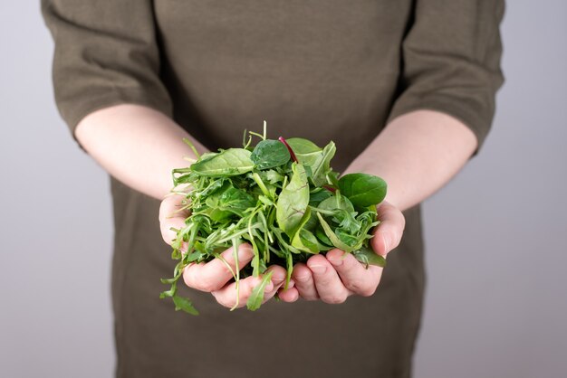 Manos femeninas sosteniendo un montón de verduras de hoja verde