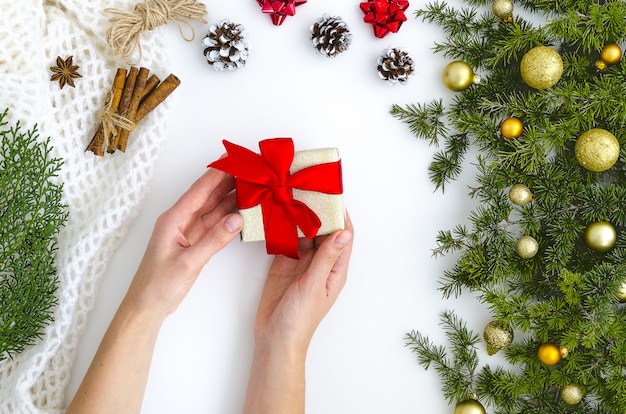 Manos femeninas sosteniendo presente, abeto, bolas de oro. Vacaciones: Navidad, Año Nuevo.