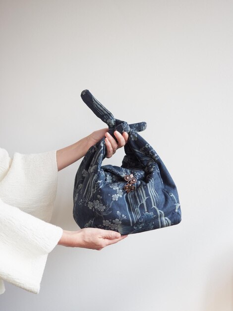 Foto manos femeninas sosteniendo un regalo en un paquete de tela reutilizable ecológico técnica furoshiki japonesa