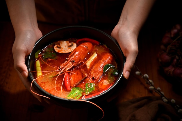 Manos femeninas sosteniendo un sabroso tazón tailandés Tom Yam Kung