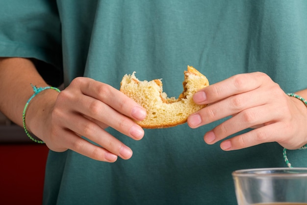 Las manos femeninas sosteniendo un sándwich de mantequilla de maní mordido con miel de pan de trigo tienen un desayuno