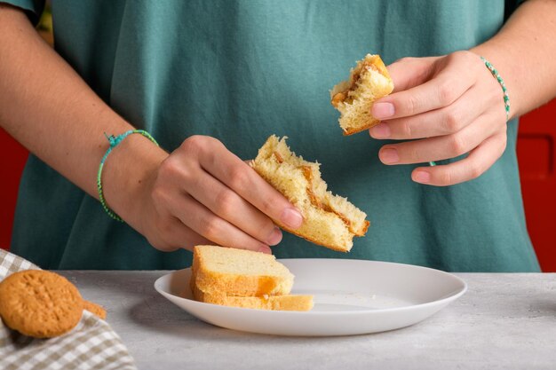 Foto las manos femeninas sosteniendo un sándwich de mantequilla de maní mordido con miel de pan de trigo tienen un desayuno