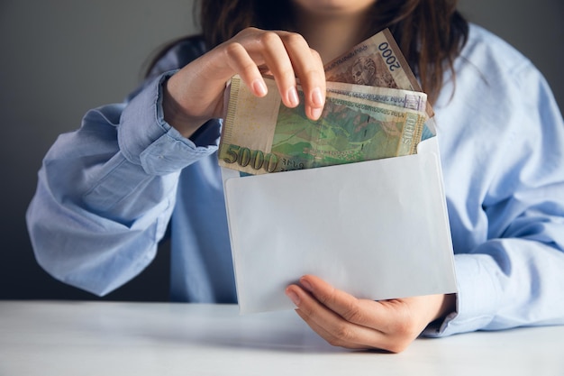 Manos femeninas sosteniendo sobre con dinero