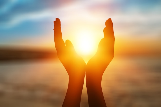 Foto manos femeninas sosteniendo el sol poniente de verano