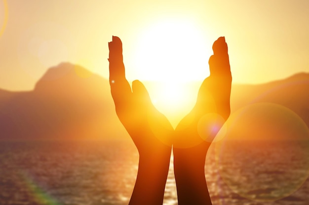 Manos femeninas sosteniendo el sol de verano que se pone