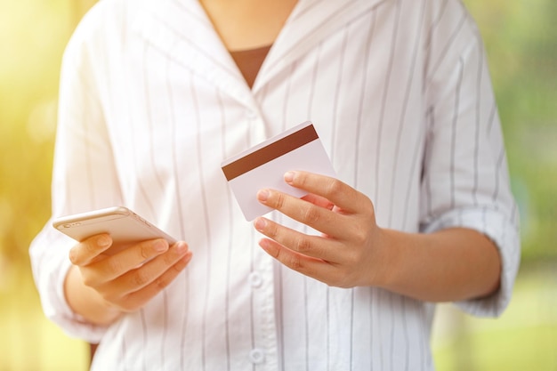 Manos femeninas sosteniendo una tarjeta de crédito y usando un teléfono inteligente. Concepto de compras en línea. Pago en línea