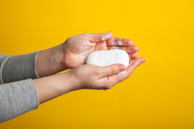 manos femeninas sosteniendo un trozo de jabón blanco