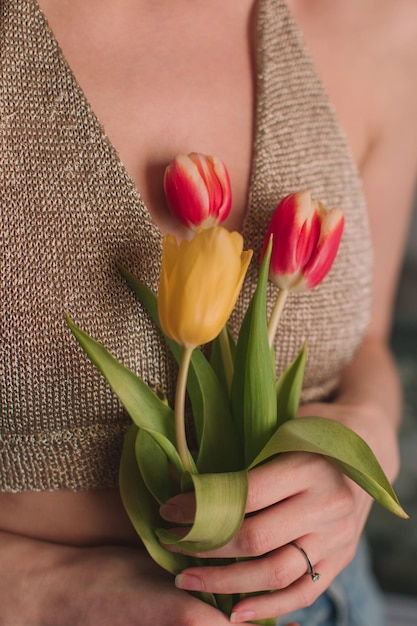 Manos femeninas sosteniendo tulipanes de flores de primavera rosas amarillas Detalles femeninos de belleza e inspiración