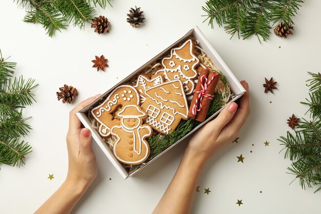 Manos femeninas sostienen caja con galleta de Navidad en blanco