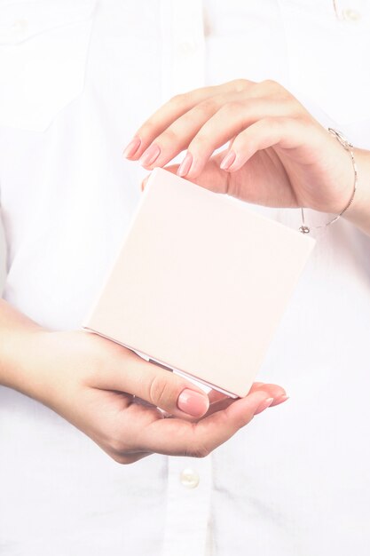 Manos femeninas sostienen una caja con un regalo en colores pastel