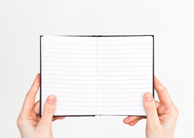 las manos femeninas sostienen un cuaderno abierto con páginas en blanco. educación, concepto de negocio