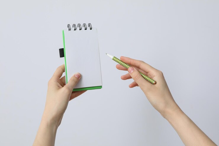 Manos femeninas sostienen un cuaderno y un rotulador