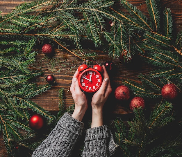 Foto manos femeninas sostienen el despertador junto a la decoración navideña