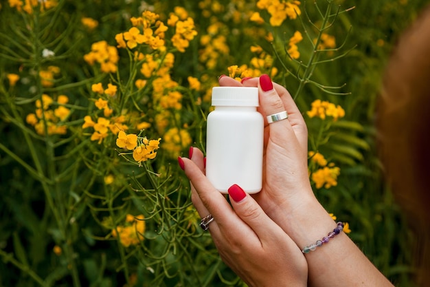 Las manos femeninas sostienen un frasco blanco contra