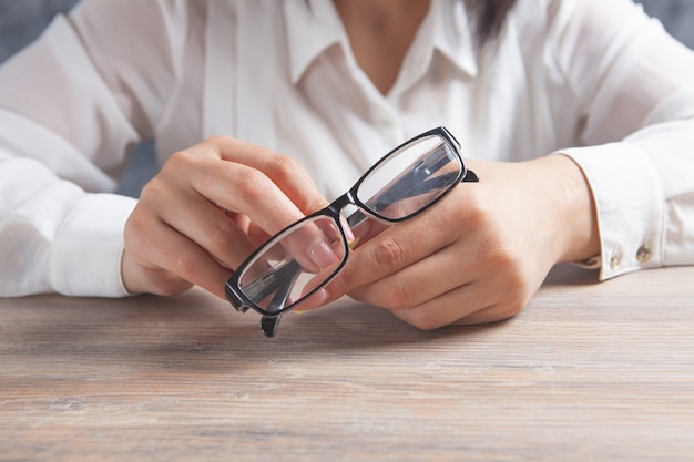 Manos femeninas sostienen gafas ópticas en la mesa