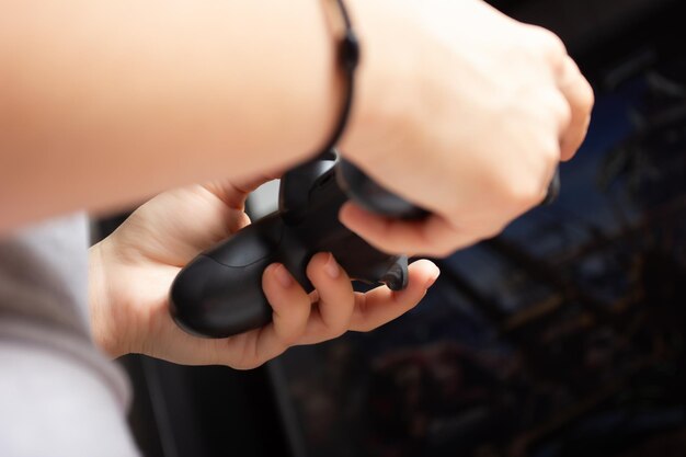 Las manos femeninas sostienen el joystick, una niña juega un videojuego