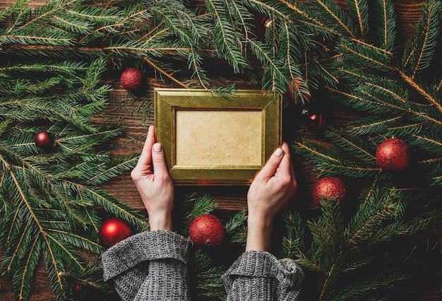 Manos femeninas sostienen el marco de fotos junto a la decoración navideña