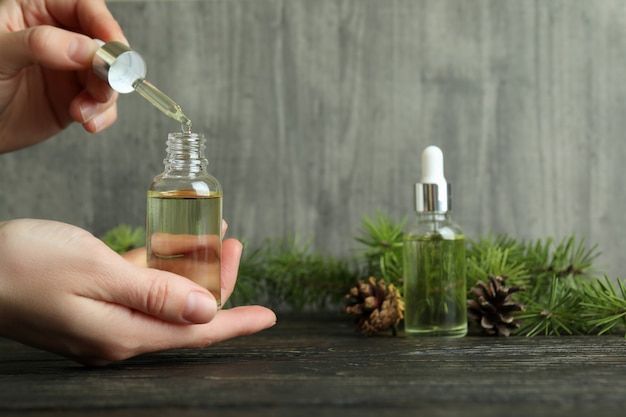 Manos femeninas sostienen pipeta y botella con aceite de pino