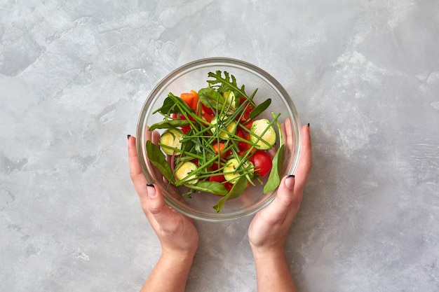 Manos femeninas sostienen un plato con ensalada fresca