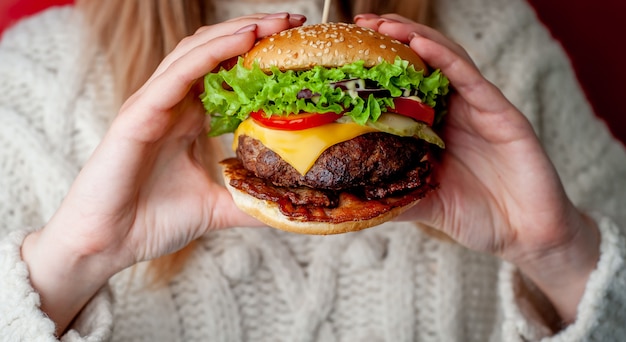 manos femeninas sostienen sabrosa hamburguesa casera