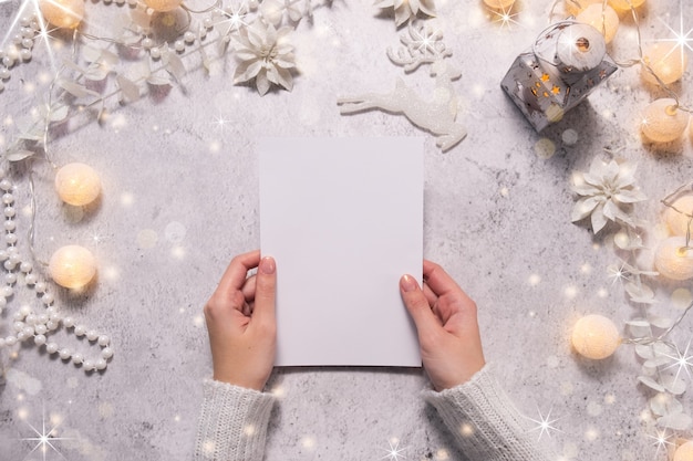 Las manos femeninas sostienen una tarjeta de Navidad. Ambiente festivo durante la época navideña. Bosquejo