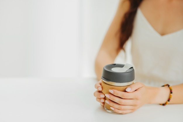 Las manos femeninas sostienen la taza de café reutilizable en una cafetería. Estilo de vida sostenible. Concepto ecológico.