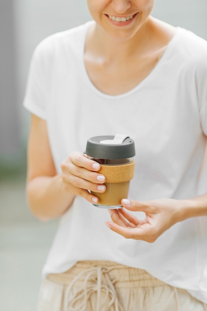 Las manos femeninas sostienen la taza de café reutilizable. Estilo de vida sostenible. Concepto ecológico.