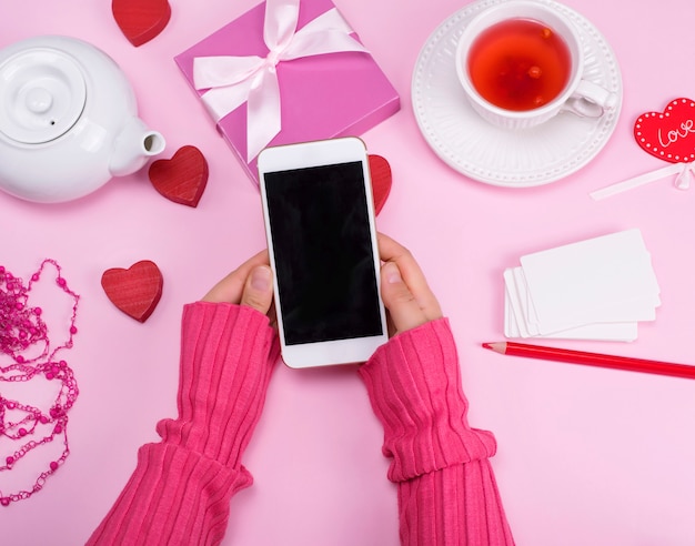 Manos femeninas sostienen un teléfono inteligente con una pantalla en blanco negro