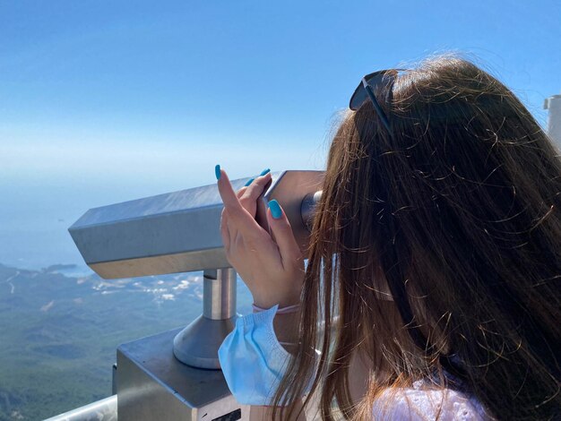 Las manos femeninas sostienen el telescopio turístico Vista desde la plataforma de observación de la plataforma de observación