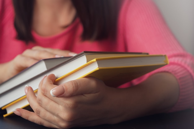 Manos femeninas sostienen varios libros nuevos.