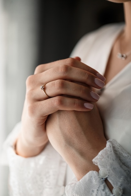 Manos femeninas suaves de la novia con un anillo de bodas de oro en el dedo anular