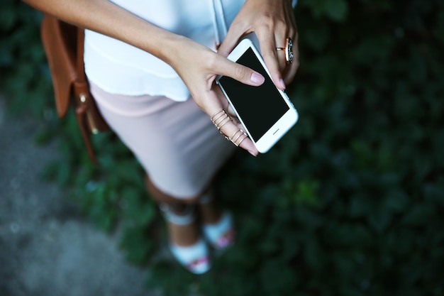 Manos femeninas con teléfono y elegantes anillos de cerca