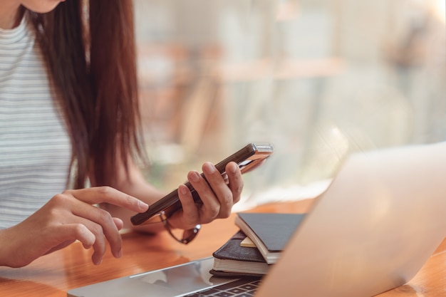 manos femeninas con teléfono inteligente en la oficina moderna. copia espacio