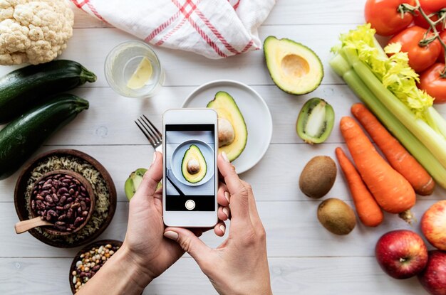 Foto las manos femeninas tomando una foto de comida saludable vista superior plana