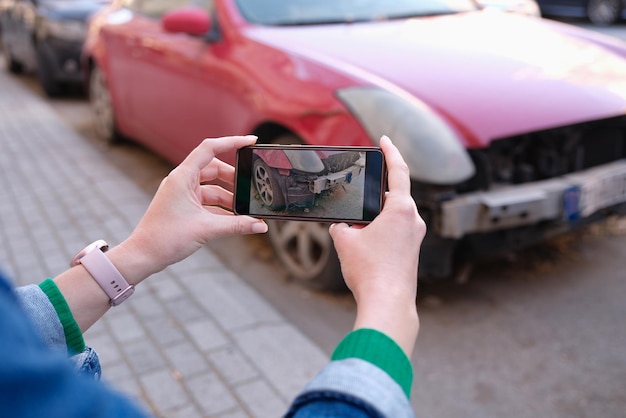 Manos femeninas tomando fotos de daños en el automóvil en el teléfono móvil closeup seguro de automóvil daños en el automóvil