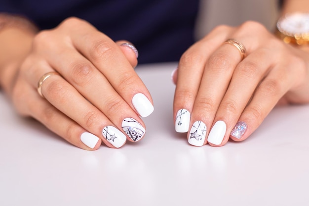 Manos femeninas con uñas de manicura de color plata.